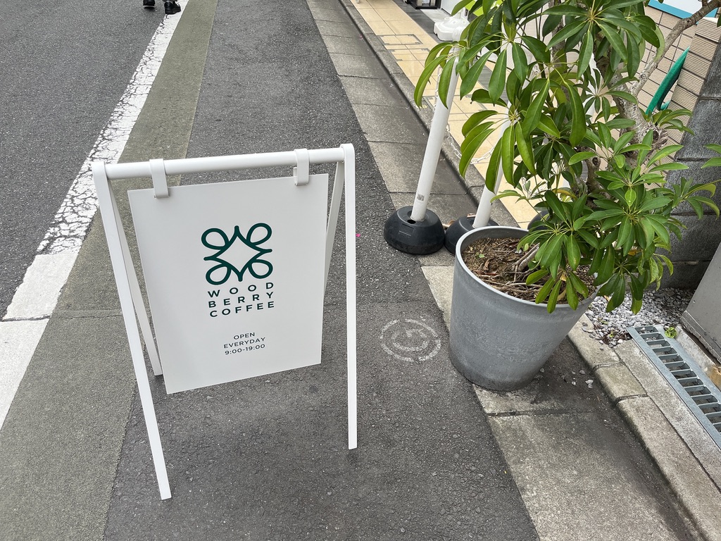 WOODBERRY COFFEEの看板。白地に緑のロゴが映えるデザイン。